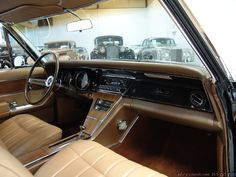 the interior of an old car with several classic cars in the background and on display