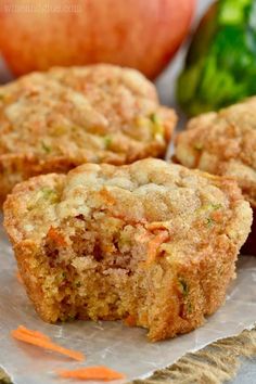 three muffins sitting on top of a piece of paper next to an apple