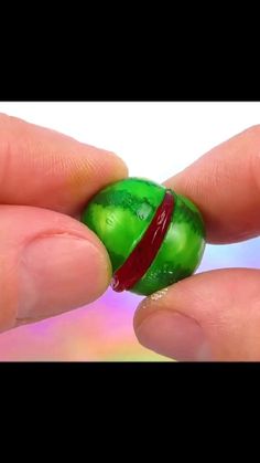 a person holding a green ring with a red band around it's middle finger