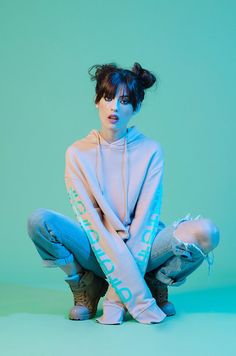 a woman sitting on the ground with her legs crossed wearing jeans and a hoodie