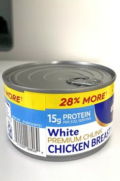 an open can of chicken breast on a white counter top with a black phone in the background