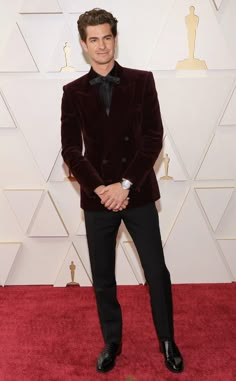 a man in a tuxedo standing on a red carpet