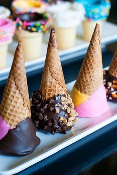 four ice cream cones with chocolate and sprinkles in them on a plate