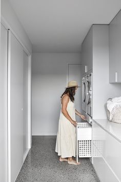 a woman in a white dress and straw hat opens the door to a washer