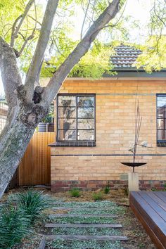 a brick house with wooden steps leading to the front door and trees in the back yard