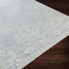 a white and blue area rug on top of a wooden floor with dark wood floors