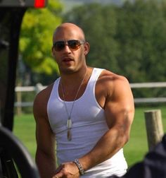 a man in white shirt and sunglasses standing next to a car