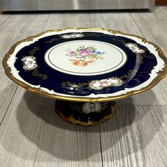 a blue and white plate with flowers on it sitting on top of a wooden table