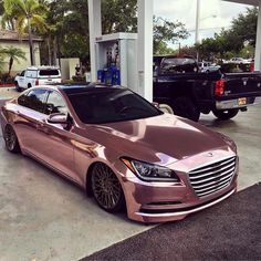 a pink car parked in front of a gas station