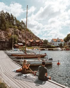 two people are sitting on the dock near boats