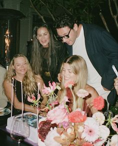 a group of people sitting around a table with cake and candles in front of them