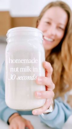 a woman holding a glass jar with the words homemade, nut milk in 30 seconds