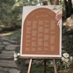 a wooden easel with a seating chart on it and flowers in the foreground