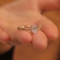 a woman's hand holding an engagement ring with a diamond on the top and side