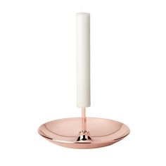 a white candle sitting on top of a pink plate