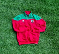 a red and green jacket laying on the grass