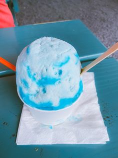 a blue and white ice cream sits in a bowl on a napkin with a wooden spoon