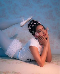 a woman laying on top of a bed with her hands under her face and wearing high heels