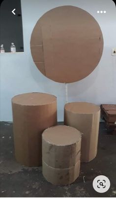 three round cardboard boxes sitting next to each other on top of a cement floor with a circular mirror in the background