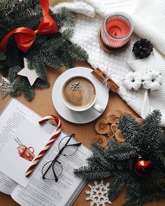 a cup of coffee sitting on top of a table next to a book and christmas decorations