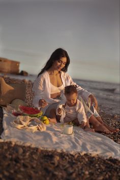 a woman and child are sitting on the beach