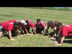 a group of young people in red shirts standing on top of a grass covered field