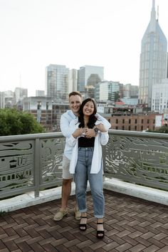 two people standing on top of a roof in front of a cityscape with skyscrapers