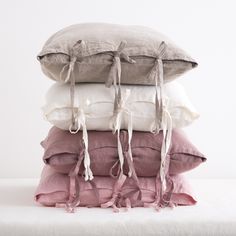 four pillows stacked on top of each other with tassels hanging from the ends