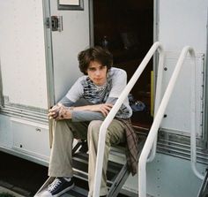 a young man sitting on top of a step ladder