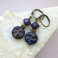 Stunning Purple Man in Moon Earrings, the perfect accessory to add a touch of celestial beauty to your jewelry collection. These handmade earrings feature Czech glass beads with brass accents.  Iridescent purple blue moon beads have detail on both sides and are topped with matte purple beads with gold flecks. Exceptionally beautiful beads.  Lightweight and comfortable to wear, these earrings are perfect for every day or special occasions. Czech glass beads are made by skilled craftsmen using traditional techniques that have been handed down through generations. Each bead is slightly different, with its own individual character and charm.  Hypoallergenic ear wires (nickel and lead free). Choose ear wire style at checkout. A gift for you or someone special, earrings are carded and in an orga Celestial Nickel-free Earrings, Celestial Nickel-free Adjustable Earrings, Adjustable Celestial Nickel-free Earrings, Adjustable Artistic Hypoallergenic Jewelry, Teardrop Earrings With Moon Charm, Teardrop Earrings With Adjustable Moon Charm, Adjustable Teardrop Earrings With Moon Charm, Moon Beads, Earthy Earrings