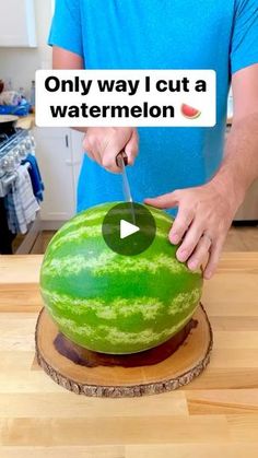 a man cutting up a large watermelon on top of a wooden countertop