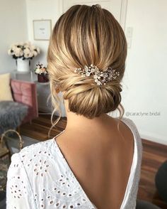 a woman with blonde hair wearing a white top and a flower clip in her hair