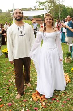 a man and woman dressed up in medieval clothing standing next to each other on the grass