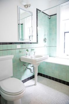 a white toilet sitting next to a bath tub under a bathroom mirror above a sink