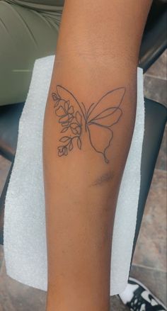 a woman's leg with a tattoo on it that has a butterfly and flowers on it