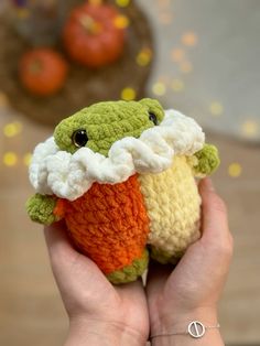 a hand holding a small crocheted stuffed animal with an orange and white face