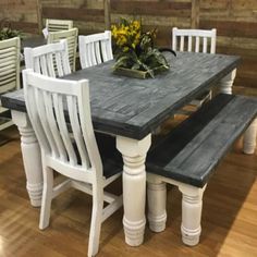 a wooden table with white chairs around it and a plant on top of the table