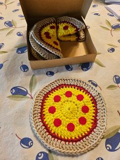 two small crocheted pizzas in a box on a table