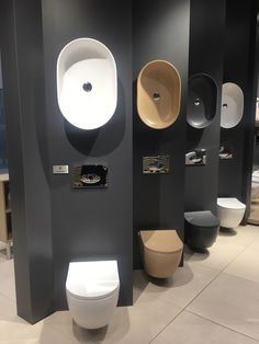 a row of toilets sitting next to each other in a room with sinks and toilet paper on the walls