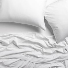 a bed with white sheets and pillows on it