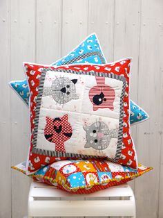 two pillows sitting on top of each other in front of a white wooden wall,