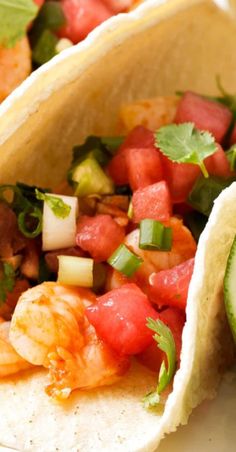 two tacos with shrimp, avocado and tomatoes