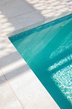 an empty swimming pool with blue water and white tile flooring is seen from above