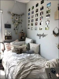 a bedroom with pictures on the wall and a bed covered in white sheets, pillows and blankets