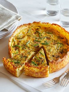 a quiche on a plate with a fork and glass of water in the background