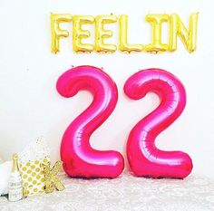 the number twenty two balloons are in front of a white wall with gold foil decorations