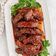 meat with sauce and parsley on a white platter