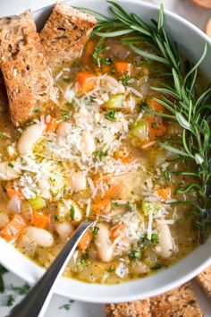 a white bowl filled with soup next to crackers and bread on top of a table