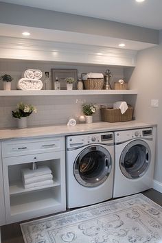 a washer and dryer sitting in a room next to a shelf filled with towels