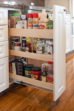 an open cabinet in the middle of a kitchen with lots of spices and condiments